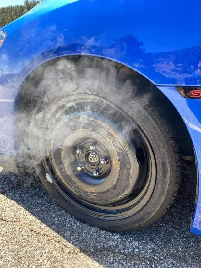 Wedged temporary spare tire mounted over Subaru WRX STI caliper turns