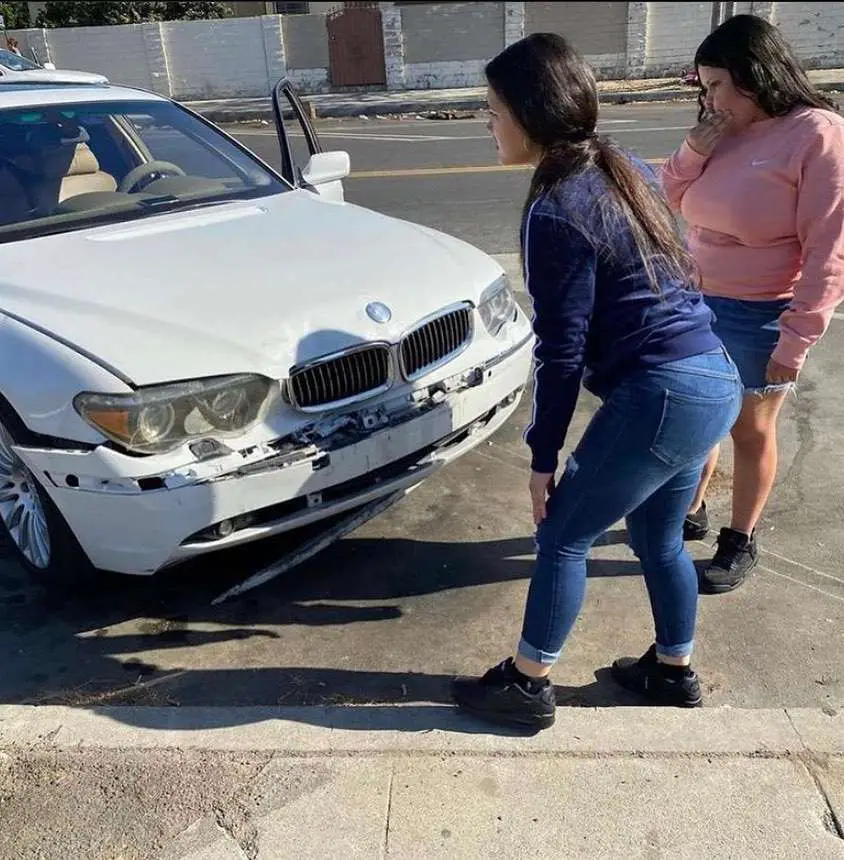 distracted BMW driver in Watts Los Angeles inspects damaage