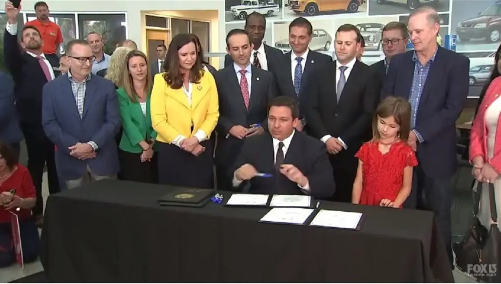 Florida Governor DeSantis signing a bill at a Honda dealership