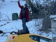 Girl takes selfie while yellow car sinks into the Rideau River in Manotick, ON