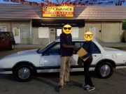 A customer and their new to them car in front of 2nd Chance Auto Sales with their faces replaced with emojis for privacy
