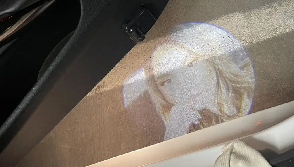 A photo of a girl's face is projected from door-mounted LED projectors