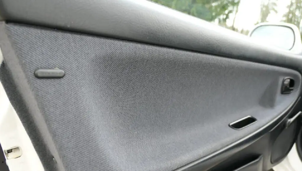 The door of a Mazda MX-3 with a conductive plastic button for dissipating static electricity