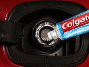 A tube of toothpaste in front of a fuel filler intake tube