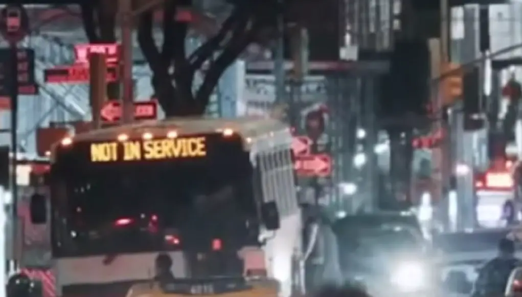 An out of service bus makes its way down a busy city street at night
