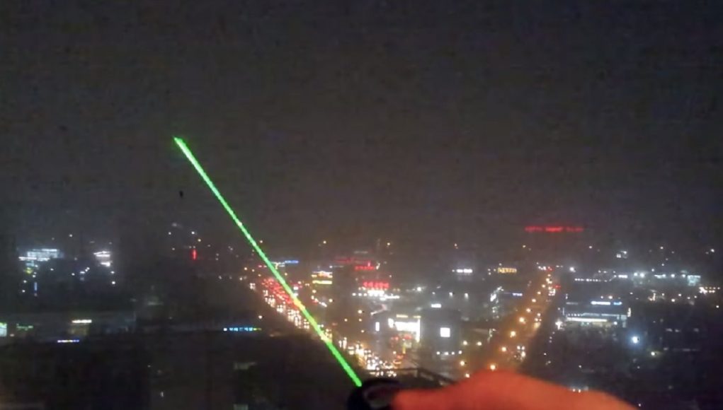 A green laser pointer shining into the night sky