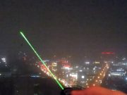 A green laser pointer shining into the night sky