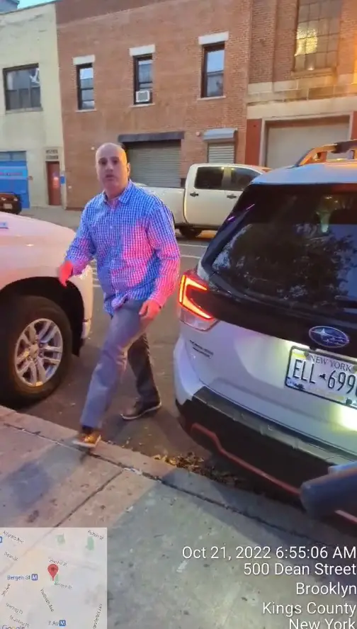 A New York City police officer attempts to park on the sidewalk but is blocked by a pedestrian on a bike