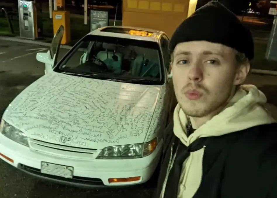 Love from the H3 Podcast posing for a selfie with his Honda Accord, the hood covered in writing.