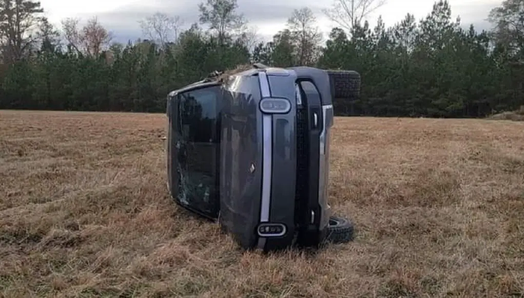 A Rivian R1T truck rolled on its side after driving on farmland