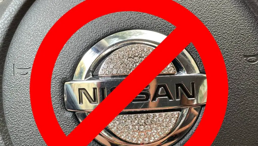 A rhinestone steering wheel emblem on a Nissan crossed out as a warning