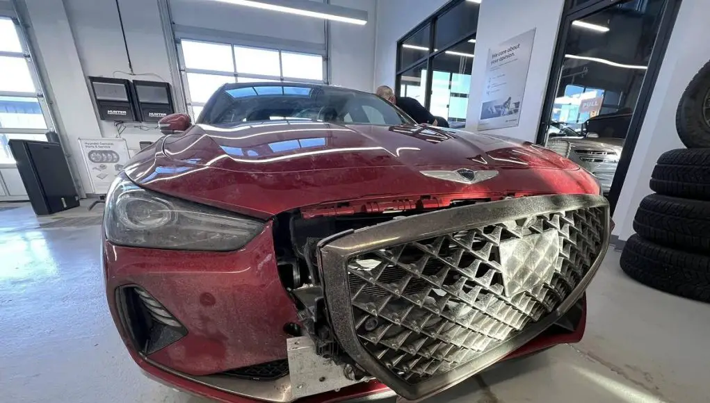 A Genesis G70 with a destroyed front end due to a tow hook mishap