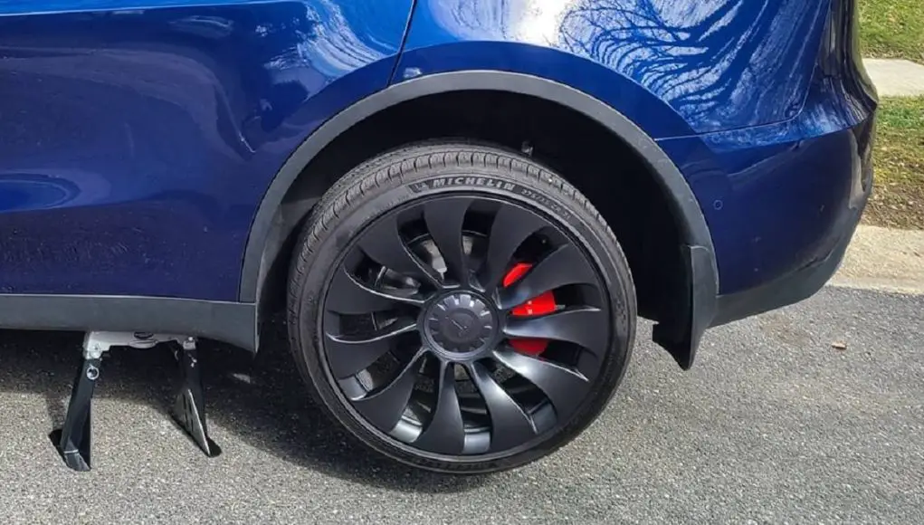 A Tesla Model Y with its rear wheel jacked up