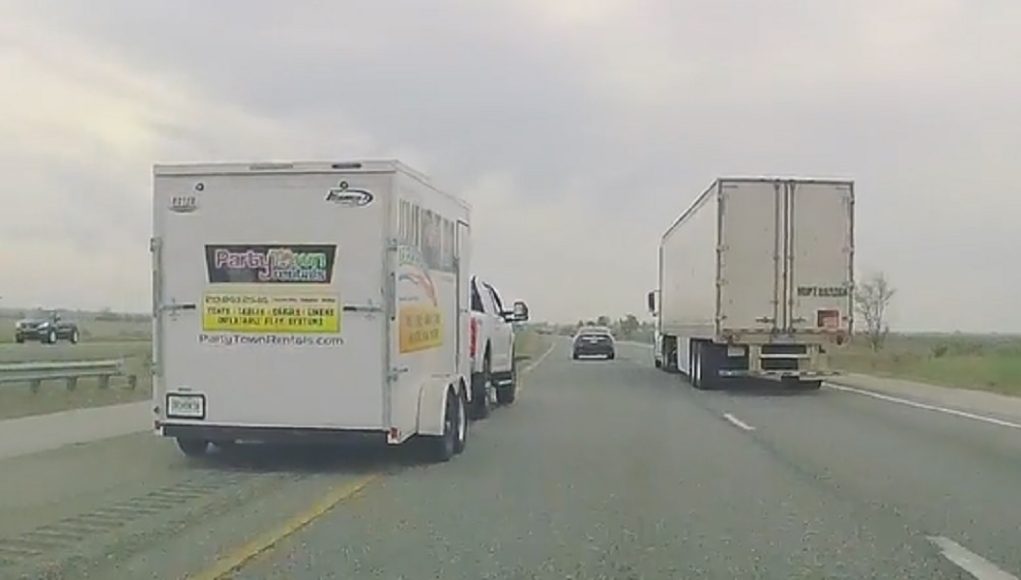 Ford F-150 towing trailer drives onto the hard shoulder of