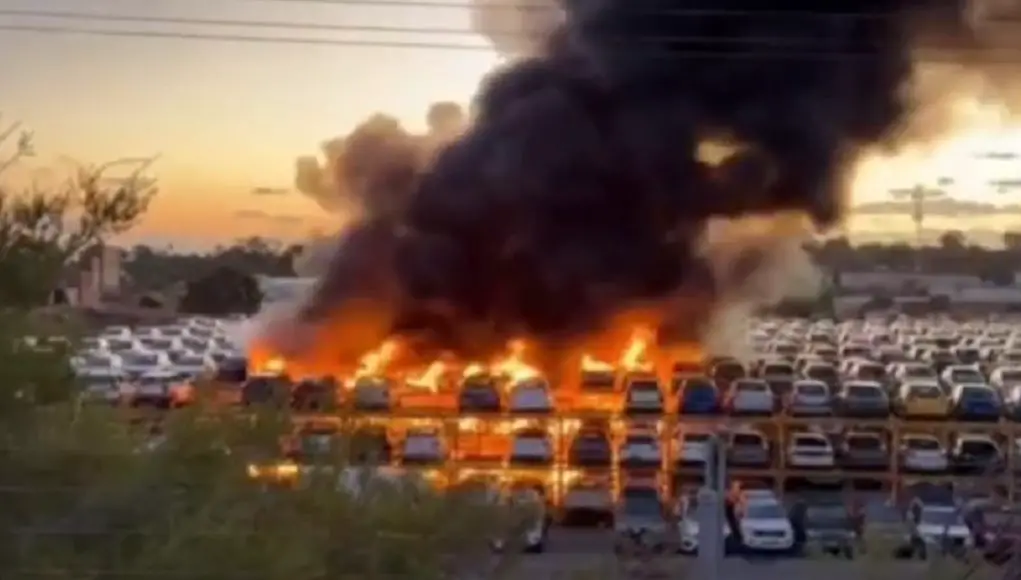 Stacked cars on fire at an auction yard.