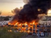 Stacked cars on fire at an auction yard.