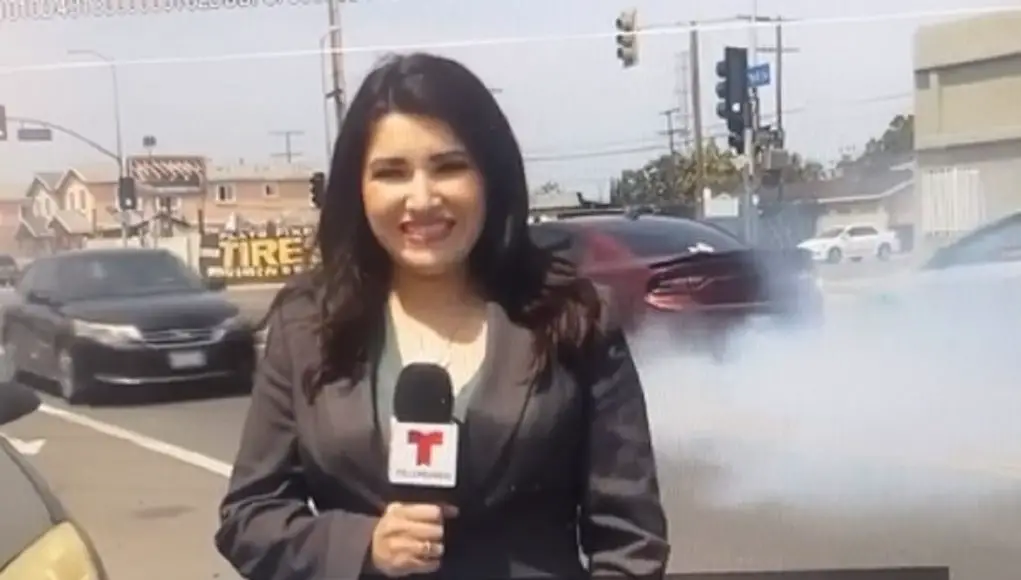 A driver in a Dodge Charger does a burnout while news reporter is reporting.