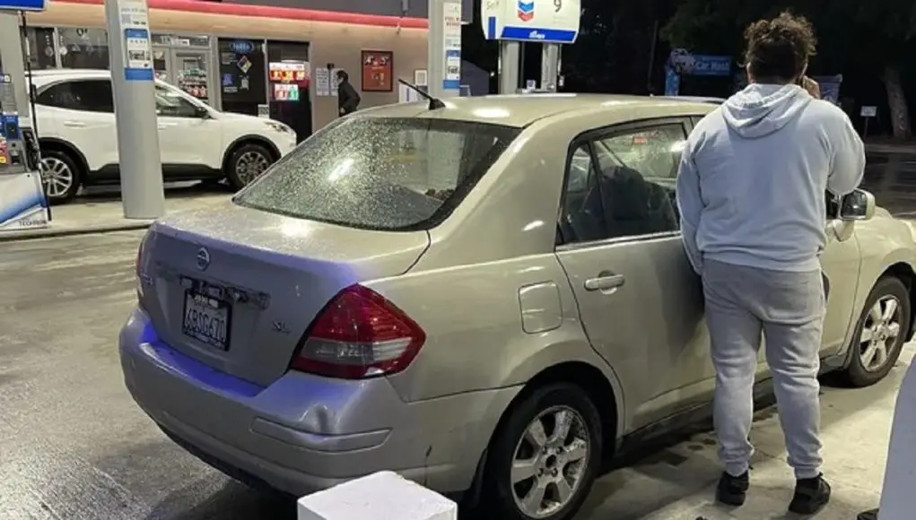 gas pump nozzle switch theif standing next to his car