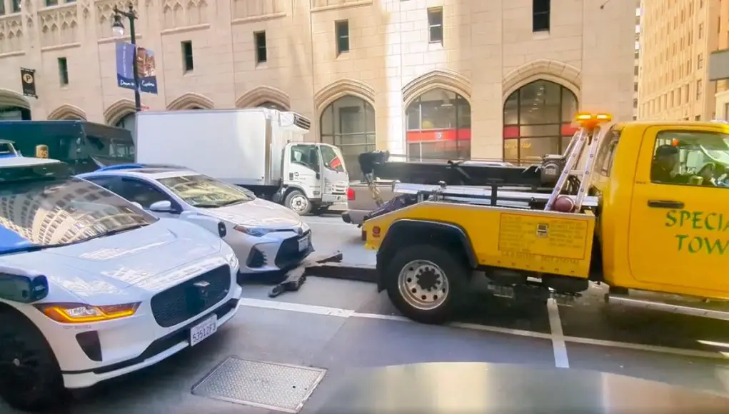 Crazy tow truck driver tries to tow car with someone driving it.