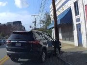 A black Chevrolet Traverse after hitting a light pole in Downtown Durham, the front end of it demolished and pracitcally totaled from an insurance point of view.