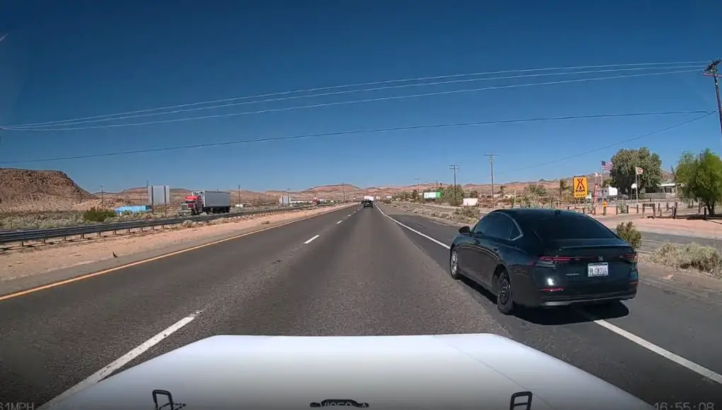 Reckless driver on spare tire on I-15 uses emergency shoulder and gore point to overtake on the right.