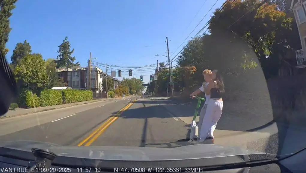 Teens riding tandem on e-scooter on 105th St. almost swerve into dashcam owner. Others caught running red light.