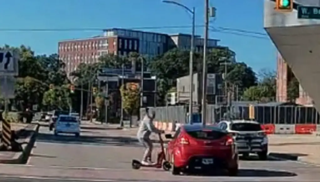 Brain-dead College scooter rider blasts through busy intersection against no-crossing signal. Gets clipped by innocent driver sending him to the concrete.