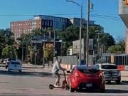 Brain-dead College scooter rider blasts through busy intersection against no-crossing signal. Gets clipped by innocent driver sending him to the concrete.