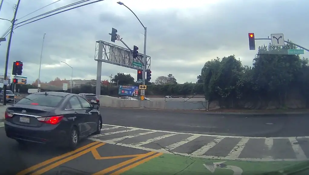 Driver at Pulgas and East Bay Shore pulls off insane move, driving against traffic and over double solid yellow to run red.